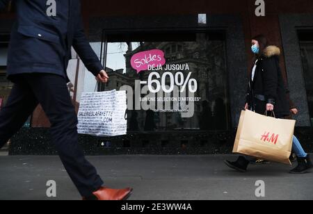 Paris, Frankreich. Januar 2021. Die Menschen gehen an einem Einkaufszentrum mit einer Werbung vorbei, die Rabatte in Paris, Frankreich, fördert, 20. Januar 2021. Kredit: Gao Jing/Xinhua/Alamy Live Nachrichten Stockfoto