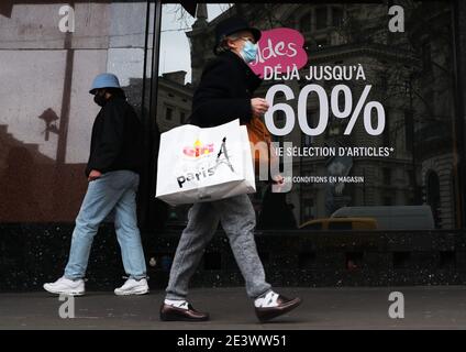 Paris, Frankreich. Januar 2021. Die Menschen gehen an einem Einkaufszentrum mit einer Werbung vorbei, die Rabatte in Paris, Frankreich, fördert, 20. Januar 2021. Kredit: Gao Jing/Xinhua/Alamy Live Nachrichten Stockfoto