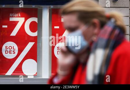 Paris, Frankreich. Januar 2021. Eine Frau geht an einem Geschäft vorbei, in dem eine Werbung für Rabatte in Paris, Frankreich, am 20. Januar 2021, angezeigt wird. Kredit: Gao Jing/Xinhua/Alamy Live Nachrichten Stockfoto