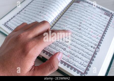 Nahaufnahme der Hand beim Lesen des Heiligen Quran in der Moschee. Selektiver Fokus. Stockfoto