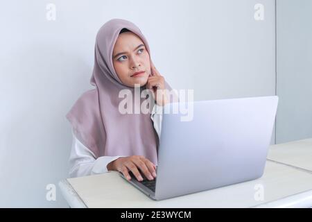 Junge asiatische Islam Frau trägt Kopftuch setzt einen Finger auf die Wange mit dem Denken und Blick bis zu kopieren Raum. Erfolgreicher Islam Indonesisch wom Stockfoto