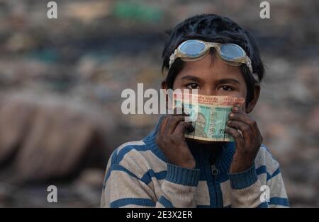 Neu Delhi, Indien. Januar 2021. Der zehnjährige Shekh Zahid zeigt das Geld, das er nach dem Verkauf von recycelbaren Gegenständen beim Sammeln von Müll auf der Bhalswaer Mülldeponie verdient hat. Der Viertklässler aus Malda in Westbengalen, dessen Vater als Rikscha-Fahrer arbeitet, begann während der Aussperrung im Oktober 2020 zu arbeiten, als Schulen geschlossen wurden. Seine Familie schickte ihn nach Delhi, um bei einem Onkel zu bleiben, der bereits als RAG Picker arbeitete. Shek verdient 150 Rupien, etwa 1.70 Euro, pro Tag durch das Sammeln von recycelbarem Material aus der Mülldeponie. Quelle: Vijay Pandey/dpa/Alamy Live News Stockfoto