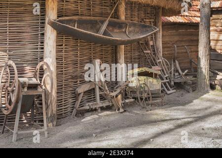 Ein Fragment einer Bauernhütte unter einem Strohdach, ein Boot, Ausrüstung und Werkzeuge für die landwirtschaftliche Arbeit. Stockfoto