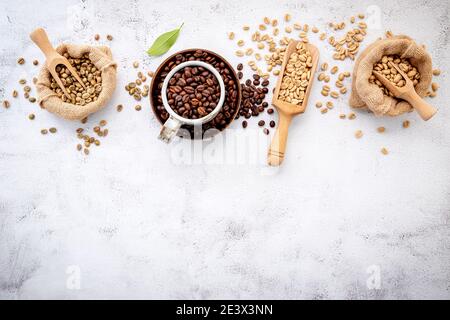 Grün und braun entkoffeinfrei geröstet und dunkel geröstet Kaffeebohnen in Hanf Sack Taschen mit Kugeln Setup auf weißem Beton Hintergrund. Stockfoto