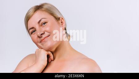 Ältere Frau mit sauberer und feuchtigkeitsspendender Haut nach Schönheitsbehandlungen lächelt und blickt auf einem weißen Hintergrund mit leerem Seitenraum in die Kamera. Stockfoto