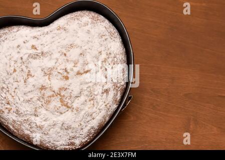 Herzförmiger Kuchen in Springform, mit Liebe frisch gebacken und mit Puderzucker bestäubt Stockfoto