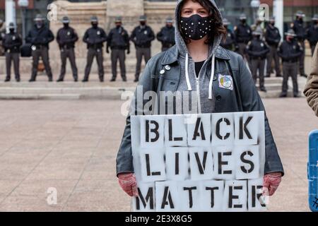 Frau hält ein Black Lives Matter Zeichen vor einer Linie von Ohio State Troopers in aus dem Ohio Statehouse. Aktivistengruppen in Columbus kamen zusammen, um die "Einheitsfront gegen das rechtsextreme und kapitalistische System" zu bilden! Diese Demonstration begann am Rathaus von Columbus, marschierte zum Columbus Statehouse und endete mit einem marsch zurück zum Columbus City Hall. Linke Aktivistengruppen organisierten diese Veranstaltung, weil sie das Gefühl hatten, dass sie ihre Präsenz der extremen Rechten bekannt machen müssten, nachdem Anhänger des vorherigen Präsidenten, Donald J. Trump, am Januar das Kapitol der Vereinigten Staaten durchbrochen hatten Stockfoto