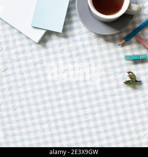 Arbeits- und Studienort. Tasse Kaffee, Notizblock, Buntstift, Clip auf blau Karomuster Stoff Hintergrund. Flach legen, Draufsicht, Kopierraum Stockfoto