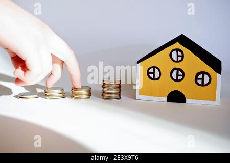 Spielzeughaus und stapelt Münzen als Symbol für Finanzen und Hypothek, Geld sparen für ein Haus Konzept. Immobilien für die Familie. Stockfoto