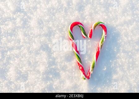 Zwei flache Zuckerstöcke bilden eine Herzform auf dem Schnee.Draufsicht. Stockfoto