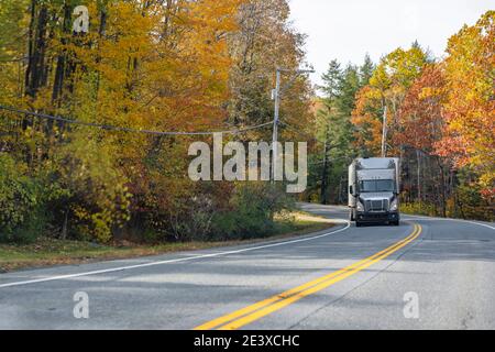 Grau Industrie Langstrecke große Rig Semi-Truck mit hoch Kabine, die gefrorene Ladung im Kühlraum transportiert, der auf dem Fahrzeug fährt Die kurvenreiche Autobahn roa Stockfoto