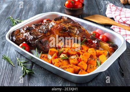 Gebackenes putenbein mit würzigen Kürbisscheiben in einem Tablett auf einem Holzhintergrund. Diät-Menü. Stockfoto