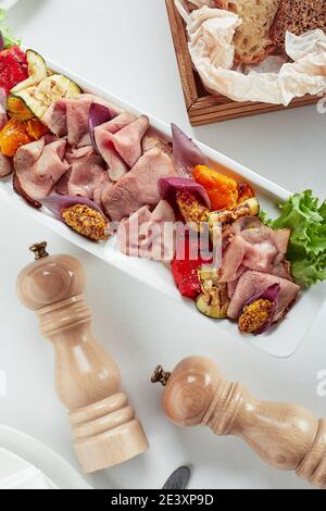 Rind- oder Schweinefleisch in Scheiben geschnitten mit mariniertem Gemüse und Sauce. Wunderschön dekoriertes Catering-Bankett-Menü. Essen Snacks und Vorspeisen für Buffet. Auf weiß Stockfoto