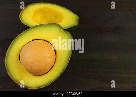 Nahaufnahme von geschnittenen frischen reifen Avocado isoliert auf schwarzem Holz Hintergrund Stockfoto