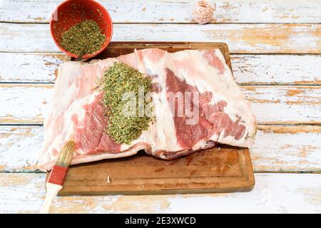 Zubereitung einer Porchetta mit einer Mischung aus aromatischen Kräutern Auf einem Stück frischen Schweinebauch offen in Die Dicke Stockfoto