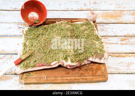 Zubereitung einer Porchetta mit einer Mischung aus aromatischen Kräutern Auf einem Stück frischen Schweinebauch offen in Die Dicke Stockfoto