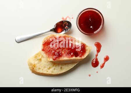 Frühstückstoast mit Erdbeermarmelade auf weißem Hintergrund, ein süßer Marmeladentoast und ein Löffel Marmelade für eine morgendliche Leckerei Stockfoto