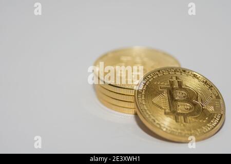 Ein Bitcoin liegt auf anderen Bitcoins, die mit gestapelt werden Hellgrauer Hintergrund Stockfoto