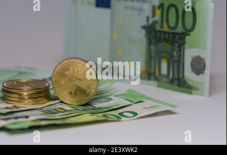 Eine stehende Bitcoin neben einem Stapel anderer Bitcoins Auf 100 Euro Scheine Stockfoto