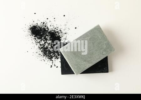 Holzkohle- und graue Naturseifenstücke mit feinem schwarzem Pulver auf Weiß, ein handgefertigtes Seifen-Flat-Lay mit einem Detox-Gefühl Stockfoto