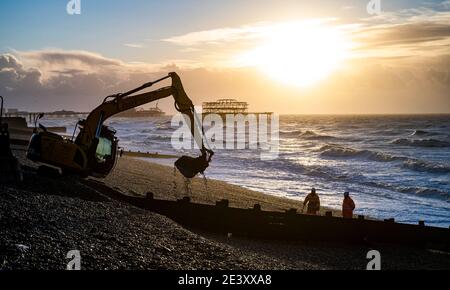 Brighton UK 21. Januar 2021 - Arbeiter trotzen den stürmischen Bedingungen am Strand von Hove, als sie bei einer Mischung aus Sonnenschein und starken Regengüssen die Kiesel abräumen, während das Ende des Sturms Christoph Großbritannien verlässt, nachdem er in Nordteilen von England und Wales Überschwemmungen verursacht hat: Kredit Simon Dack / Alamy Live Nachrichten Stockfoto