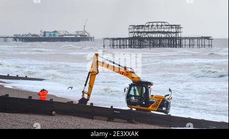 Brighton UK 21. Januar 2021 - Arbeiter trotzen den stürmischen Bedingungen am Strand von Hove, als sie bei einer Mischung aus Sonnenschein und starken Regengüssen die Kiesel abräumen, während das Ende des Sturms Christoph Großbritannien verlässt, nachdem er in Nordteilen von England und Wales Überschwemmungen verursacht hat: Kredit Simon Dack / Alamy Live Nachrichten Stockfoto