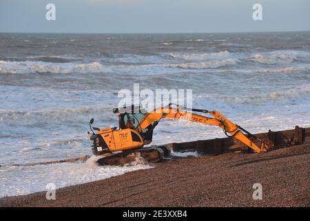 Brighton UK 21. Januar 2021 - Arbeiter trotzen den stürmischen Bedingungen am Strand von Hove, als sie bei einer Mischung aus Sonnenschein und starken Regengüssen die Kiesel abräumen, während das Ende des Sturms Christoph Großbritannien verlässt, nachdem er in Nordteilen von England und Wales Überschwemmungen verursacht hat: Kredit Simon Dack / Alamy Live Nachrichten Stockfoto