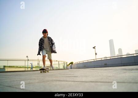 Teenager asiatische Kind Skateboarding im Freien auf einer Fußgängerbrücke Stockfoto