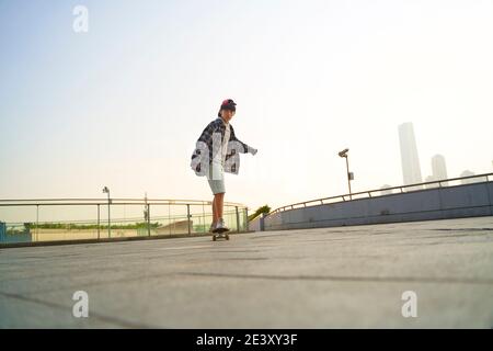 Teenager asiatische Kind Skateboarding im Freien auf einer Fußgängerbrücke Stockfoto