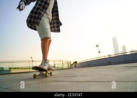 Teenager asiatische Kind Skateboarding im Freien auf einer Fußgängerbrücke Stockfoto