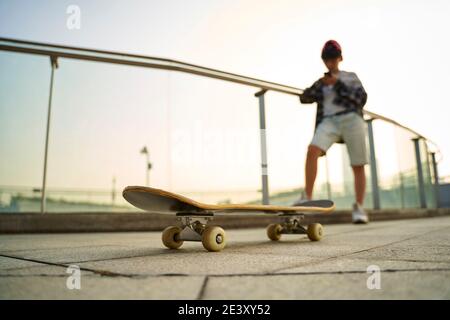 Teenage asiatische Skateboarder Junge Blick auf Handy während der Ruhe, konzentrieren Sie sich auf das Skateboard Stockfoto