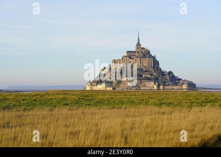 Le Mont Saint-Michel im Winter. Die Salzwiesen. Übersicht über den Berg und die Fußgängerbrücke bei Ebbe Stockfoto