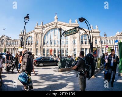 Paris, Frankreich - 20. Mai 2018: Ultra-Weitwinkel-Ansicht der französischen Straße mit ikonischen hohen Gebäude des Gare du Nord und metropolitane Art-Deco-Beschilderung große Menge von Menschen pendeln in der Pre-Covid-Ära Stockfoto