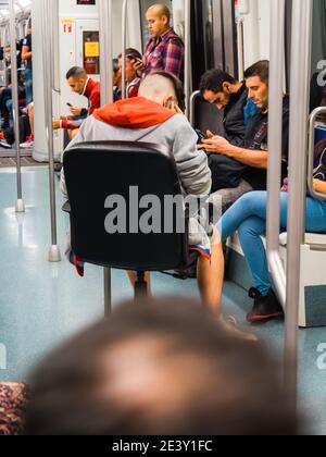 Lissabon, Portugal - 30. Mai 2, 2018: Große Menschenmenge pendelt innerhalb der Lissabon U-Bahn-Zug - Mann sitzt auf hsi eigenen Büro Lederstuhl reden auf Handy Stockfoto