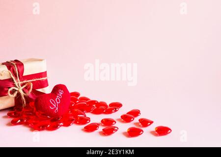 Rote Herzen und eine Geschenkbox auf einem rosa Hintergrund - Valentinstag Urlaub, Banner, Copyspace. Shopping für einen geliebten Menschen, ein Paar in der Liebe Stockfoto
