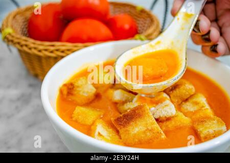 Nahaufnahme der Tomatensuppe mit Brotsuppen In einem Suppenlöffel Stockfoto