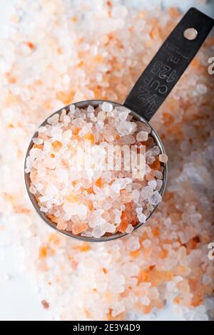 Himalaya-Salz im Messlöffel auf weißem Hintergrund. Rosafarbenes Salz. Stockfoto
