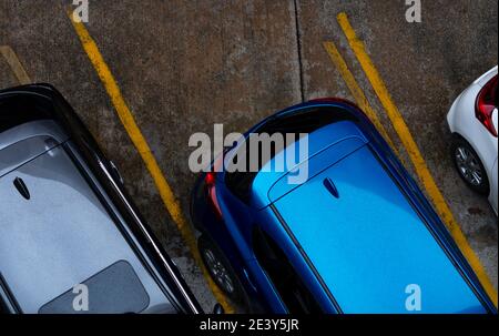 Draufsicht auf das Auto geparkt auf Beton Parkplatz mit gelben Linie der Verkehrszeichen auf der Straße. Oben Blick auf Auto in einer Reihe auf Parkplatz. Stockfoto