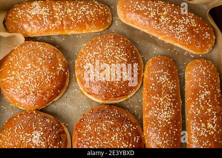 Gebackene Sesambrötchen auf braunem Pergamentpapier, Zutat für einen Hamburger, Draufsicht Stockfoto