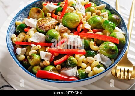 Nahaufnahme von Makkaroni-Salat mit Brokkoli-Sprossen, Paprika-Streifen, Feta und Erdnuss in einer Schüssel, horizontale Ansicht von oben Stockfoto