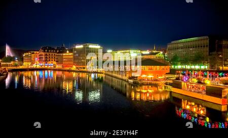 Genf, Schweiz bei Nacht. Jet d'Eau Brunnen und Skyline spiegelt sich von pont de la Coulouvreniere auf der Rhone Fluss mit Blick auf den Genfer See, Französisch Stockfoto