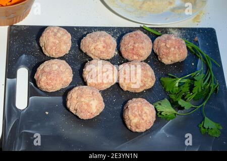 Kochen von Fleischschnitzel. Halbfertige Fleischbällchen auf einem Schneidebrett. Stockfoto
