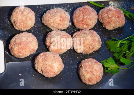 Kochen von Fleischschnitzel. Halbfertige Fleischbällchen auf einem Schneidebrett. Stockfoto