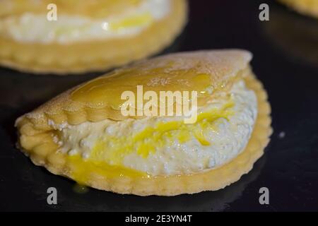 Kekse mit Hüttenkäse auf einem mit Eigelb beschmiertem Backblech. Stockfoto