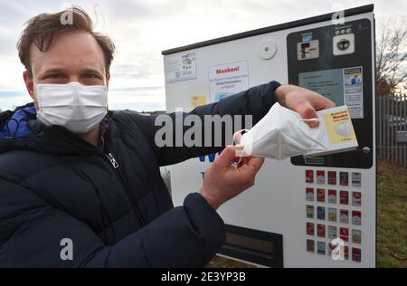 Gerolzhofen, Deutschland. Januar 2021. Menas Wolf, Geschäftsführer von Wolf Tabakwaren e.k., hält eine FFP2-Maske mit Verpackung vor einem seiner Zigarettenautomaten. Der Tabakladen bietet die Schutzmasken in seinen Automaten an. Quelle: Karl-Josef Hildenbrand/dpa/Alamy Live News Stockfoto