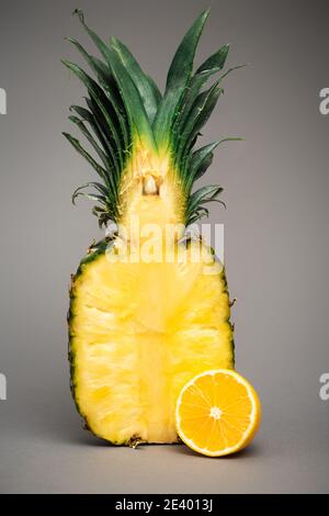Hälften von saftiger Ananas und Zitrone auf grau Stockfoto