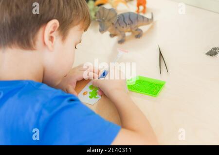 Nahaufnahme eines kleinen Jungen, der ein Diamantmosaik erstellt, selektiver Fokus. Stockfoto