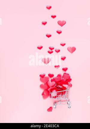 Trolley Warenkorb mit vielen Herzen auf rosa Hintergrund gefüllt. Konzept des Einkaufens für Valentinstag. Platz für Text kopieren. Stockfoto