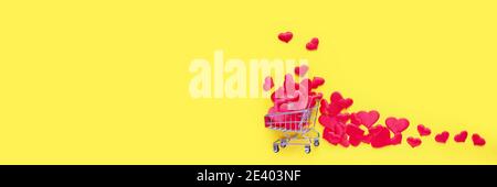 Trolley Warenkorb mit vielen Herzen auf rosa Hintergrund gefüllt. Konzept des Einkaufens für Valentinstag. Platz für Text kopieren. Stockfoto