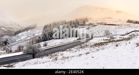 Highway Landstraße führt durch eine schöne Winter Wunderland mit Bergen und Wäldern. Lake District, Großbritannien. Stockfoto